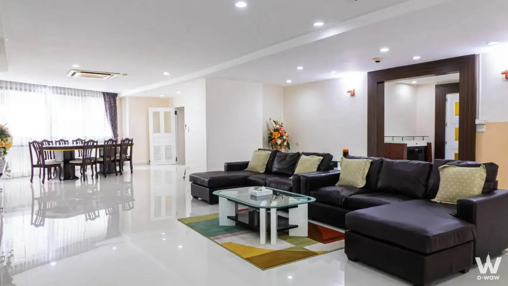 3-bed condo for sale in Park24 featuring an open-plan living area with a black leather sectional and geometric rug
