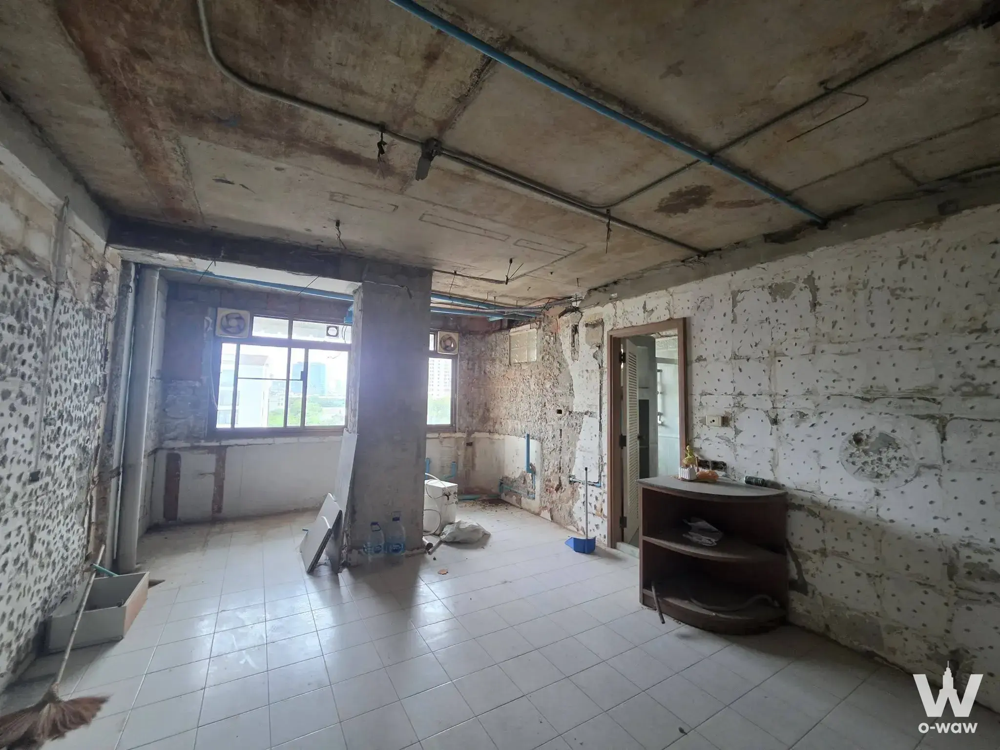 2-bed condo for sale in Green Peace Mansion showing living room under heavy renovation with exposed concrete, pipes, and