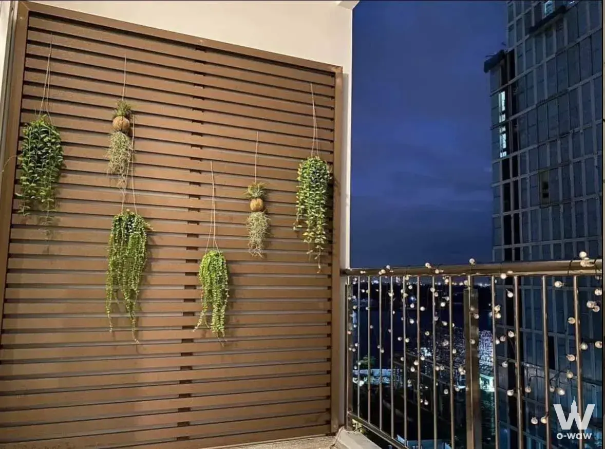 Evening balcony view from a 1-bed condo for rent in Supalai Riva Grande Rama 3 with hanging plants and string lights