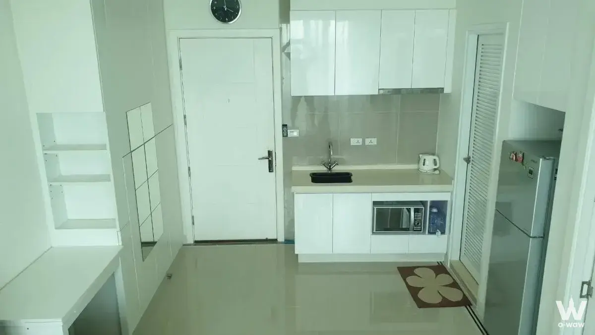 Compact kitchenette with white cabinets and fridge in a tidy studio unit at TC Green Building A