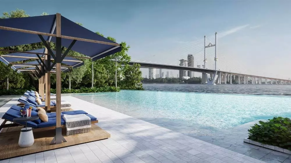Infinity pool deck at Nue Riverest Ratburana with lounge chairs and a wide river view