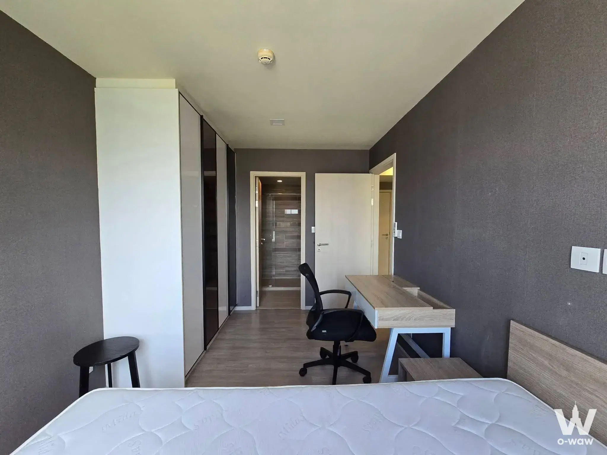 Bedroom in Maestro 03 Ratchada-Rama 9 with dark walls, built-in wardrobe, and desk near bathroom entrance