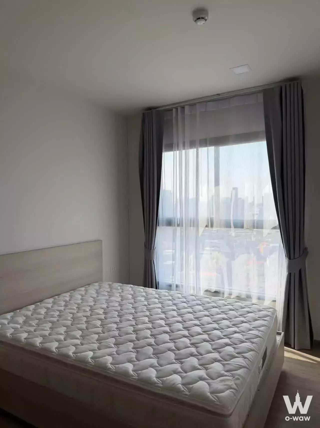 Bright bedroom in NIA by Sansiri featuring floor-to-ceiling windows and city skyline view