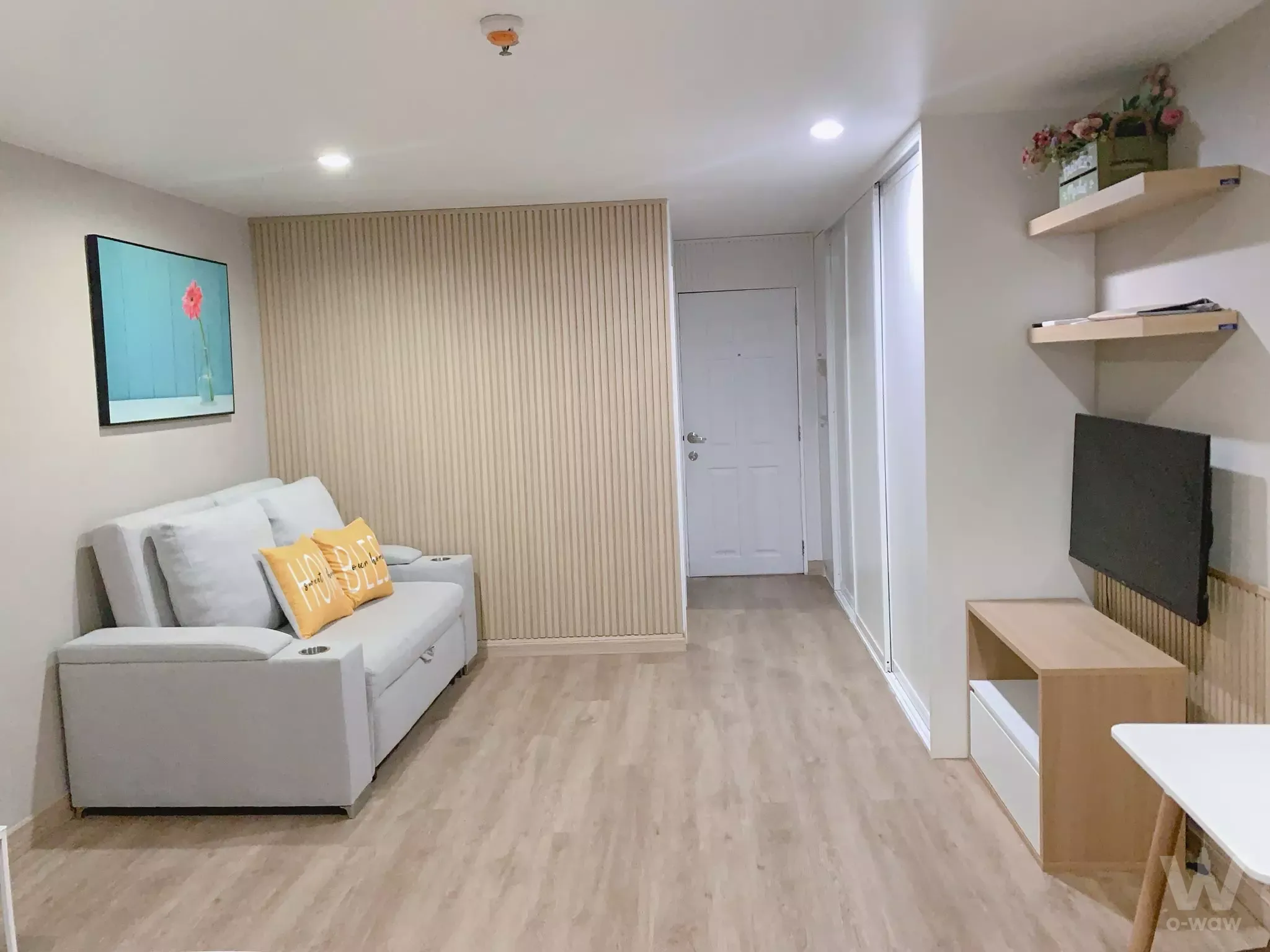 Bright living room in a Regent Home 6/1 house with grey sofa, wood slat panel, and sliding glass doors
