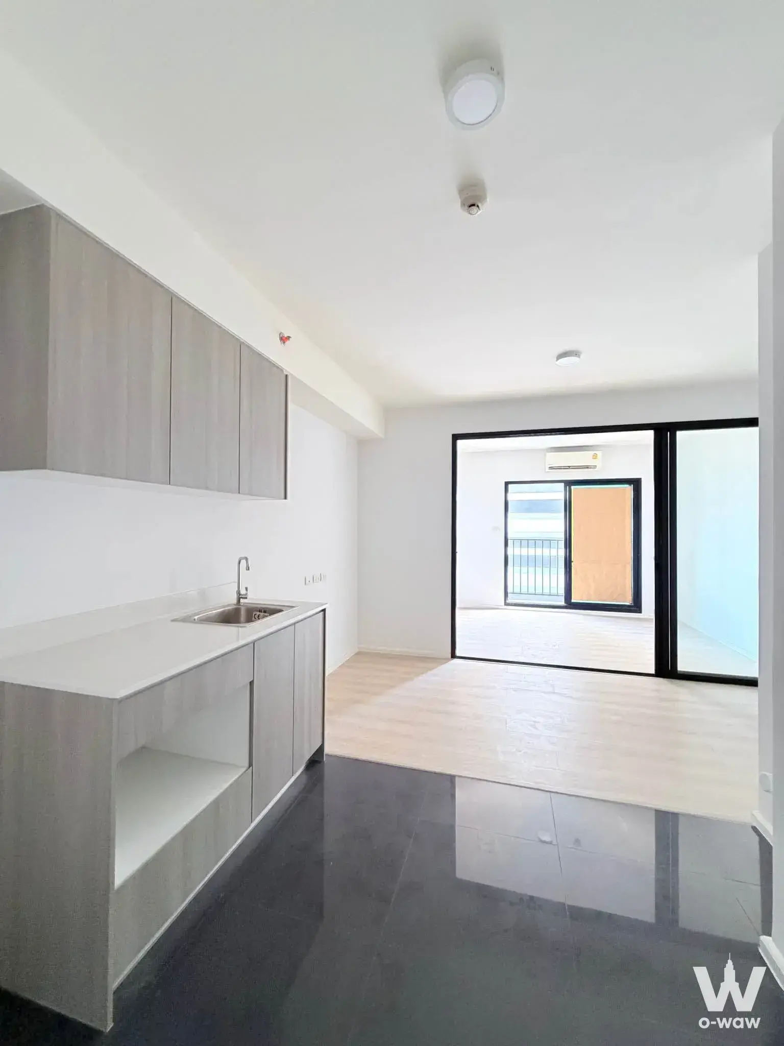 Unfurnished A Space Condominium kitchen featuring light wood cabinets white quartz counter and dark tile floor
