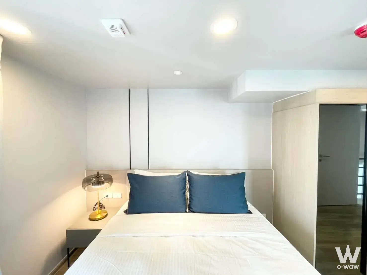 2-bed condo for rent in Culture Thonglor bedroom with blue pillows, wood floors, and modern lighting
