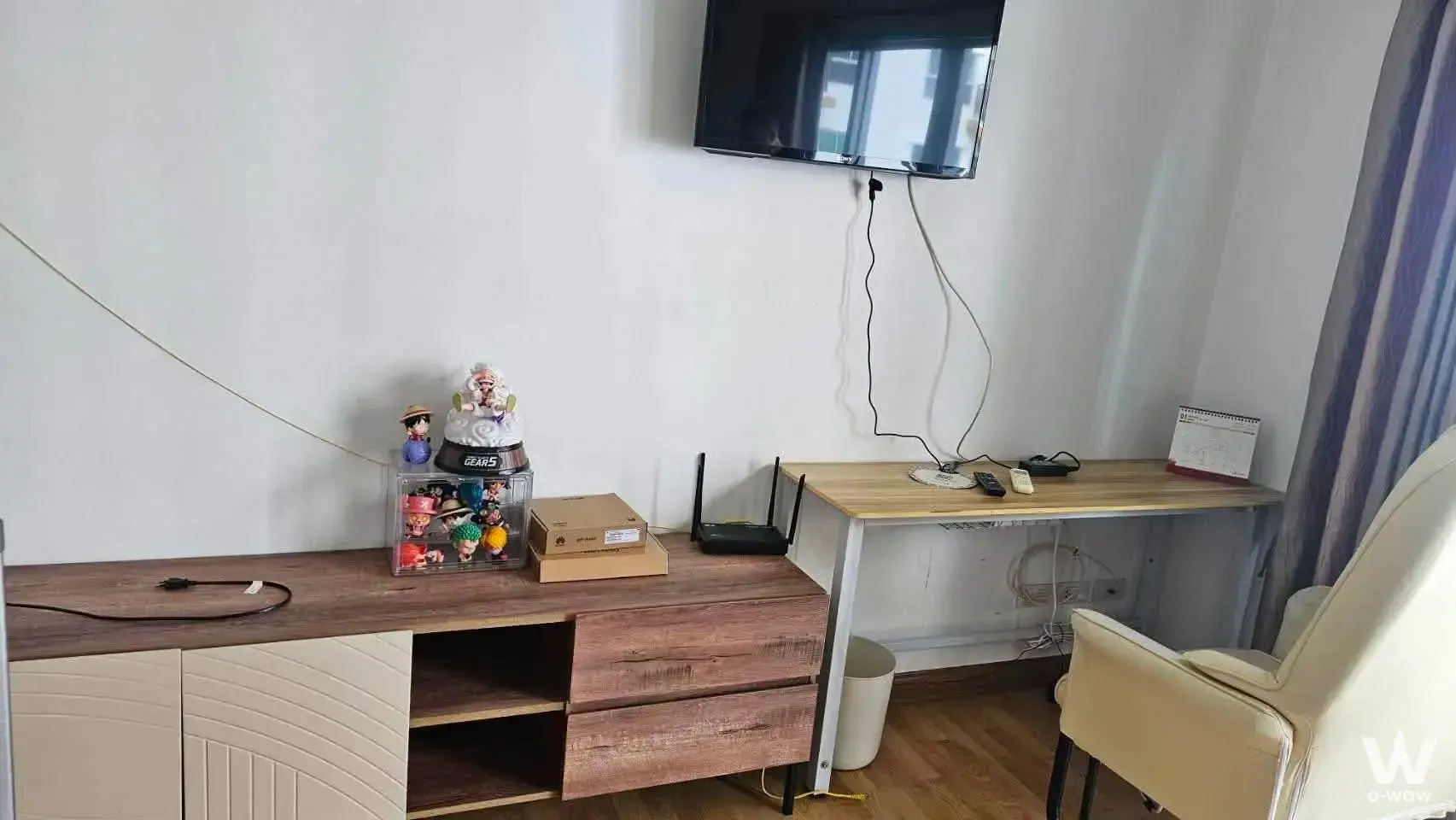 Compact living corner with wall-mounted TV and desk in a 1-bed rental at The Parkland Taksin - Tha Phra