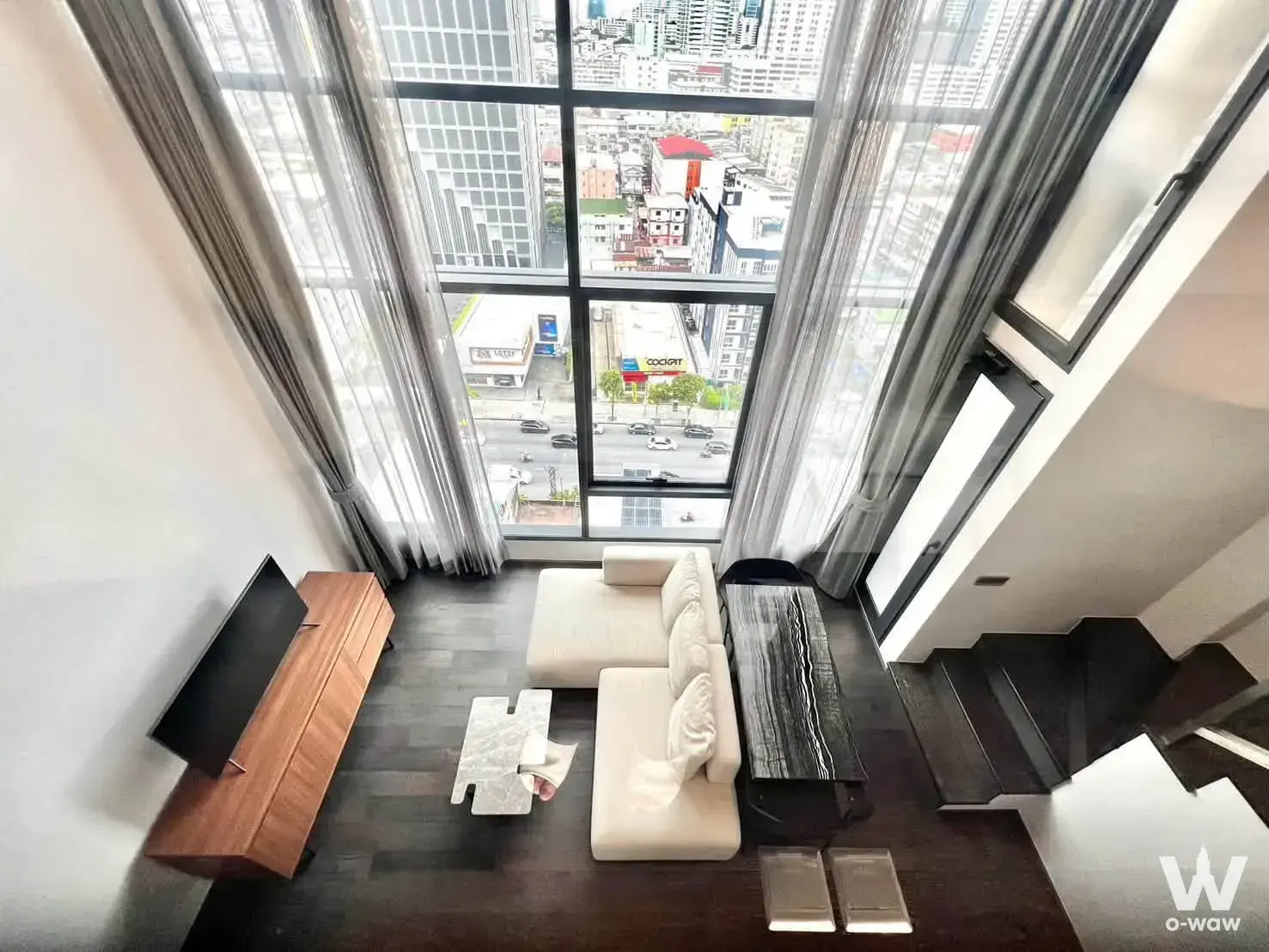 Cream L-shaped sofa and marble coffee table in a CONNER Ratchathewi 1-bed condo living room