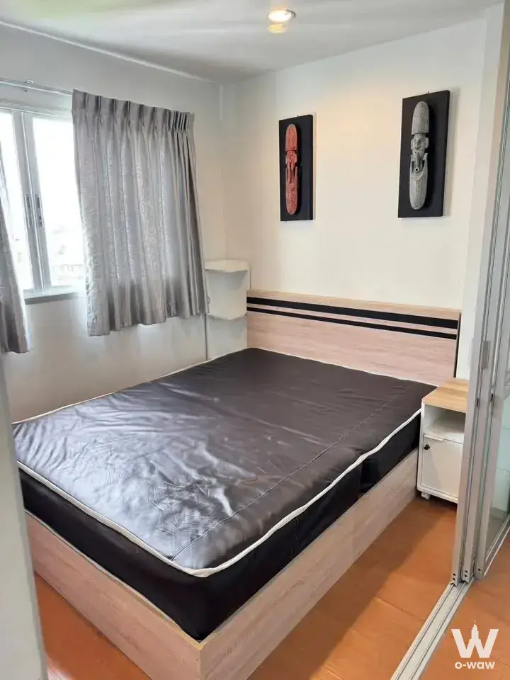 1-bed condo for rent in Lumpini Condo Town Nida SeriThai bedroom with tribal art and honey-colored flooring