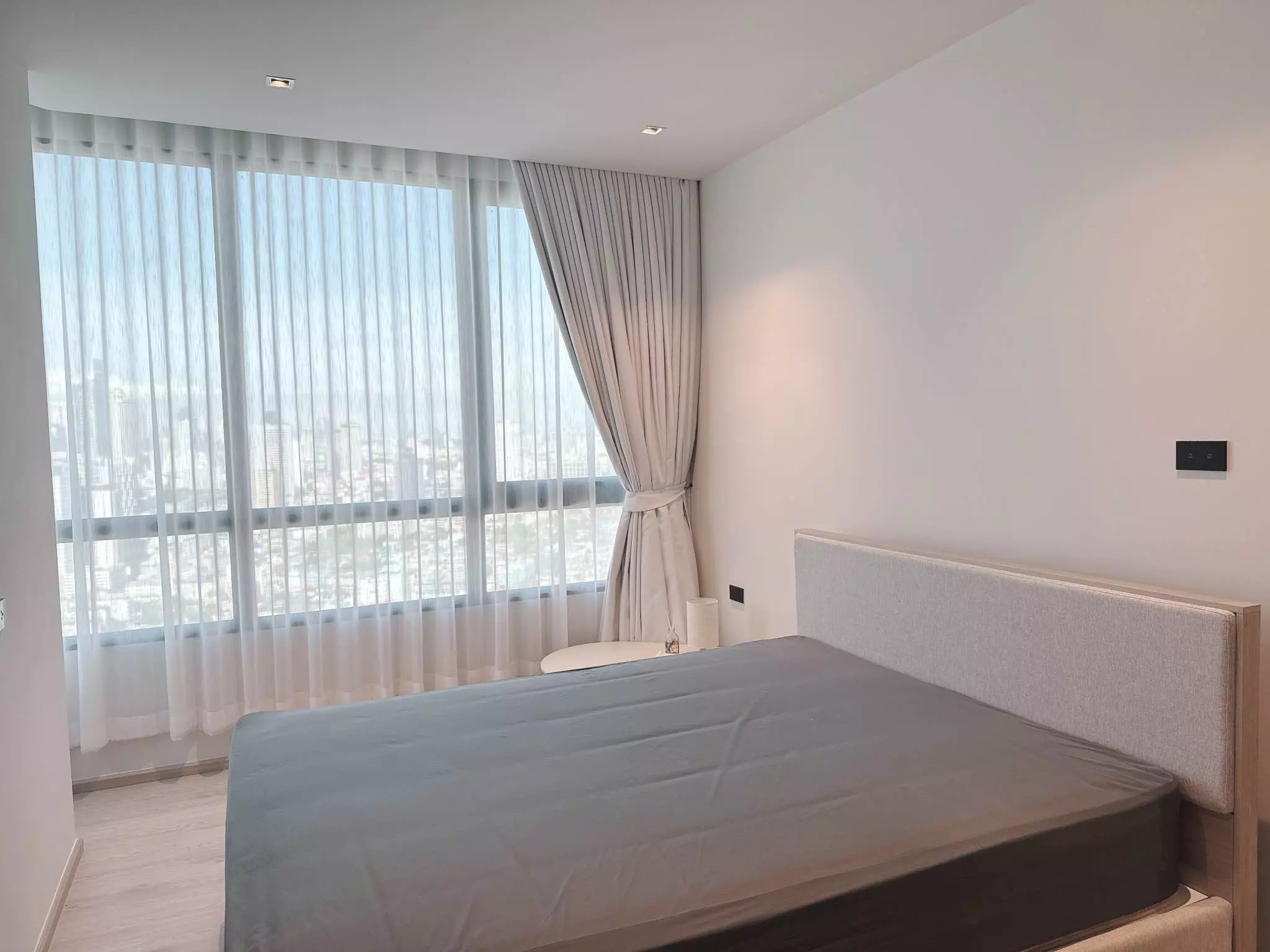 Modern bedroom with city skyline view in Reference Sathorn-Wongwianyai condo, featuring floor-to-ceiling windows