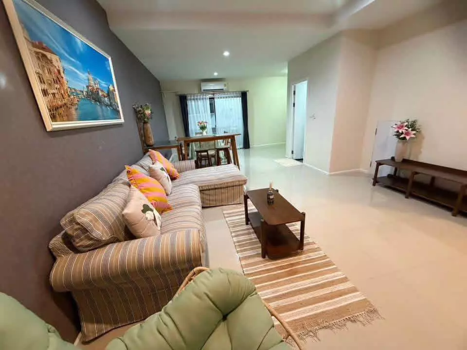 Open-plan living space with L-shaped sectional and dining set in this 2-bed Plex Residence Kaset townhouse
