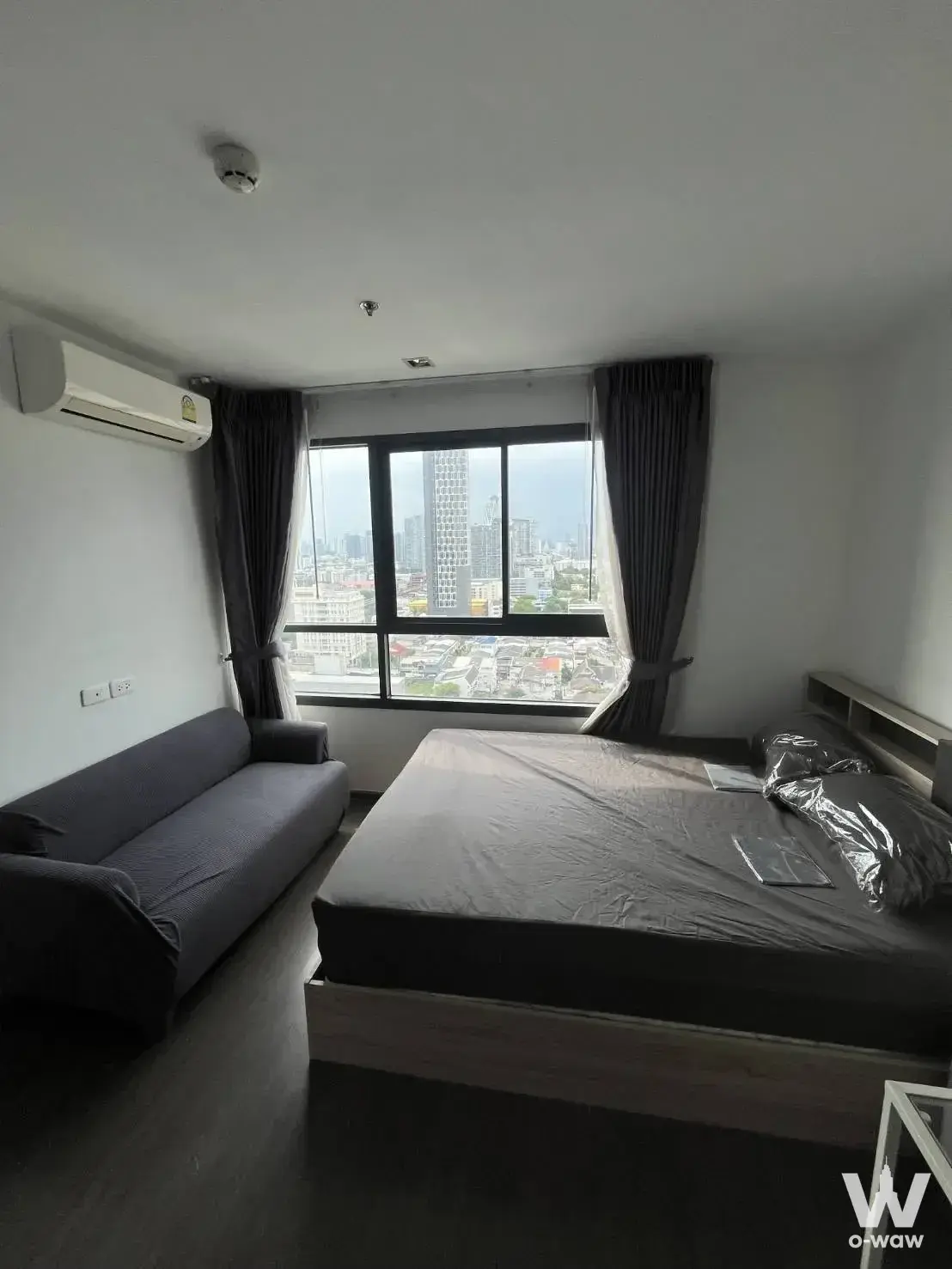 Modern bedroom in Ideo Sukhumvit 93 condo with queen bed, dark grey tones, and city view