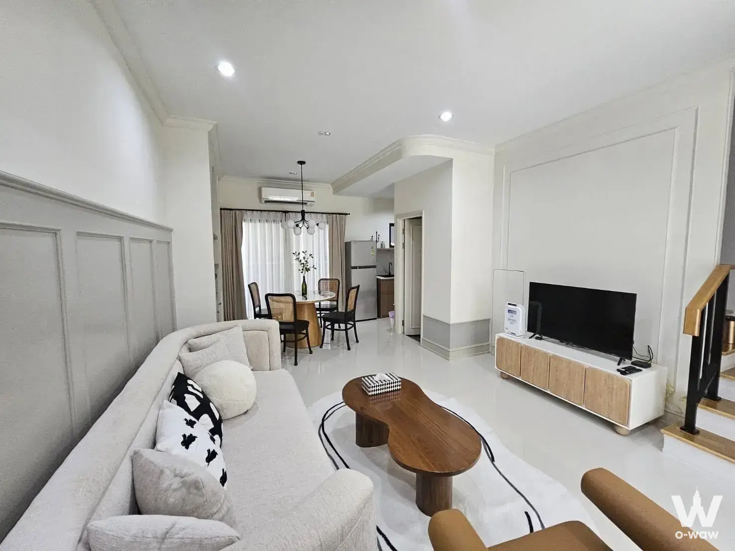 Open-plan living area in a Baan Klang Muang Rama 9 townhouse for rent with round dining table and grey wainscoting