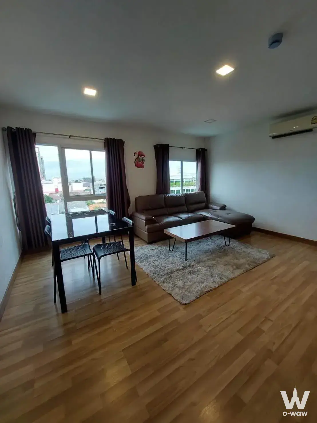 Living dining area with dark leather sofa and city view in a 2-bed condo for rent in The One Plus D Hua-mark 12