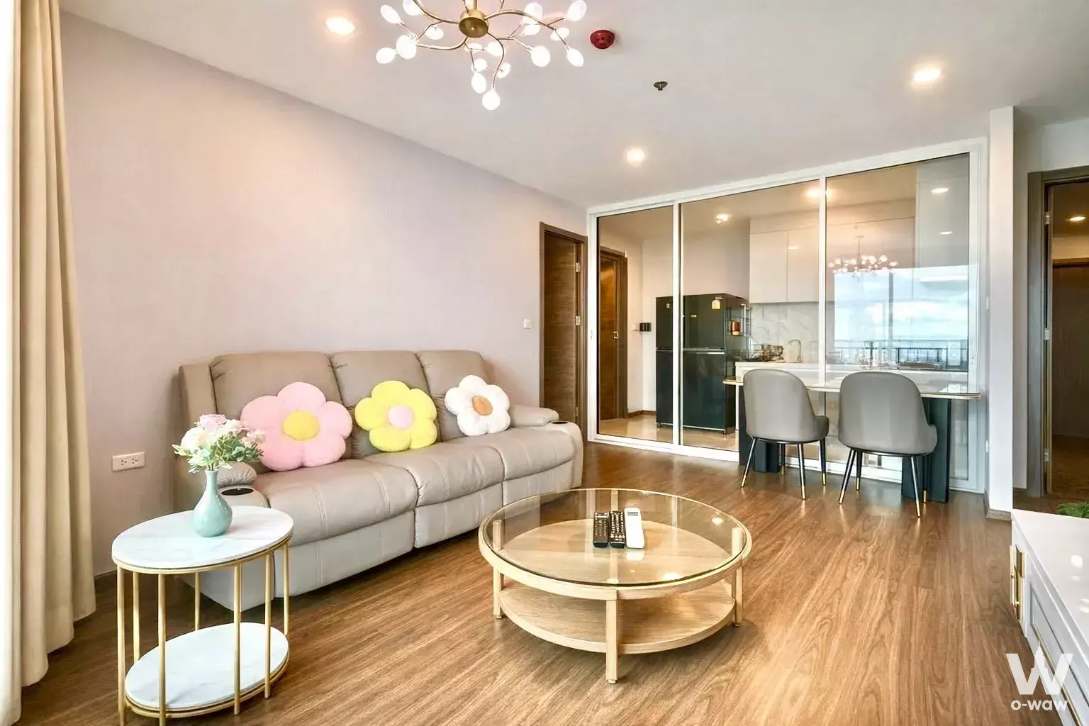Living room in a 2-bed Artisan Ratchada rental with beige leather sofa, gold accents, and a brass sputnik chandelier