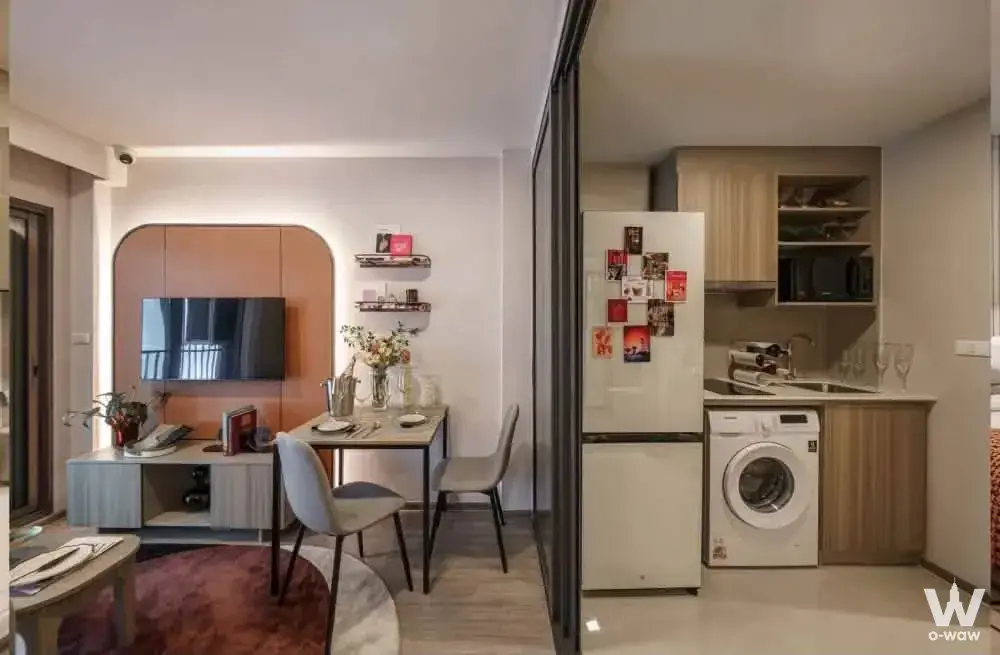 Open-plan living and kitchen in a 1-bed The Base Ratchada 19 for sale, with a terracotta TV wall and dining nook