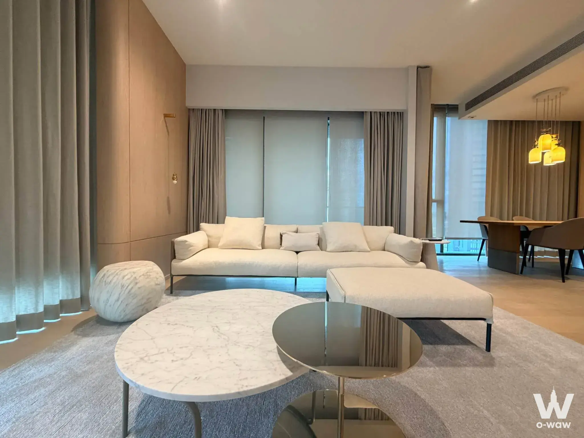 Bright living room in The Strand Thonglor condo with off-white sofa and marble coffee tables