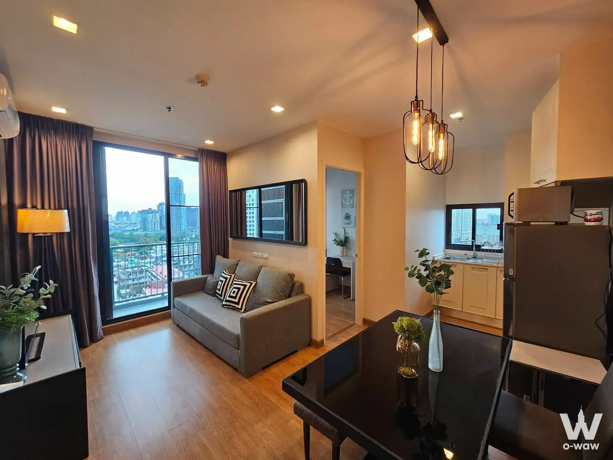 Open-plan living area with industrial lights in Q House Sukhumvit 79 2-bed condo