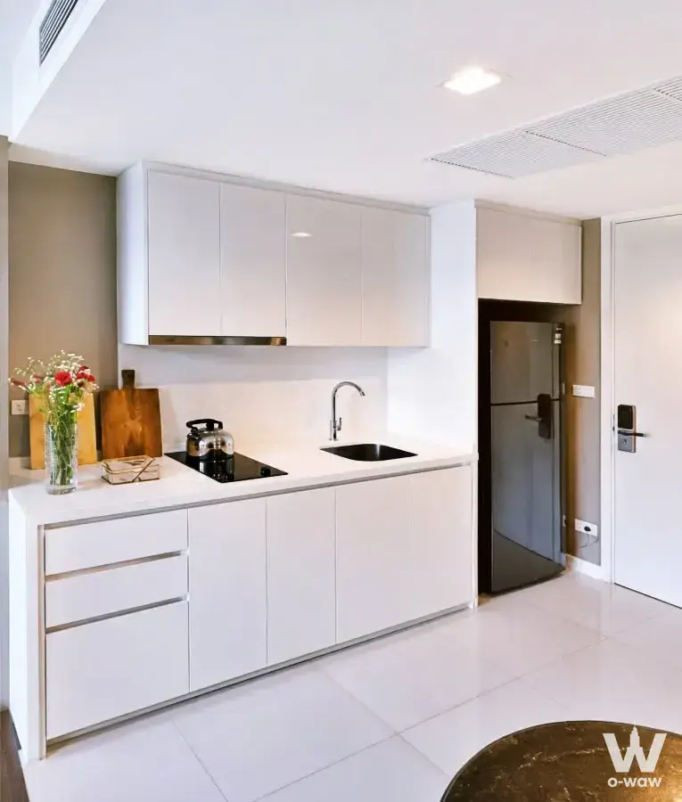 Minimalist kitchen in Nara 9 condo with white handleless cabinets and black induction cooktop