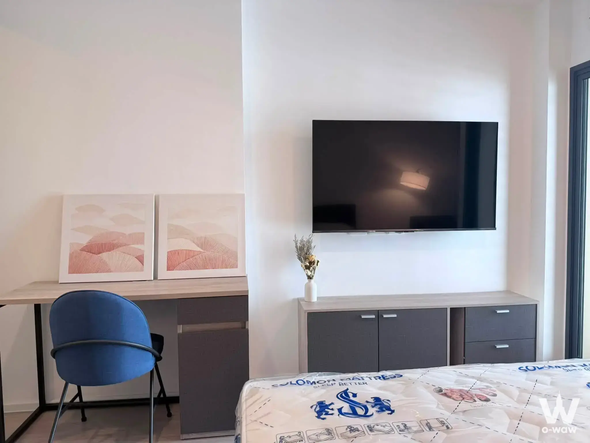 Unfurnished bedroom in DENIM Jatujak with wall-mounted TV, media console, and blue accent chair