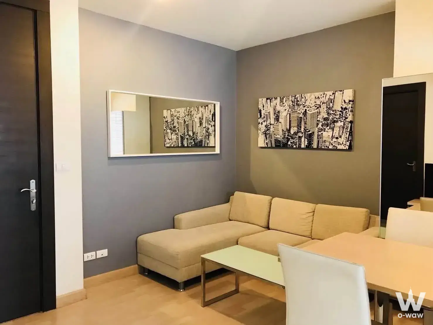 L-shaped sofa and dining area with neutral tones in a furnished 1-bed condo for rent at RHYTHM Ratchada