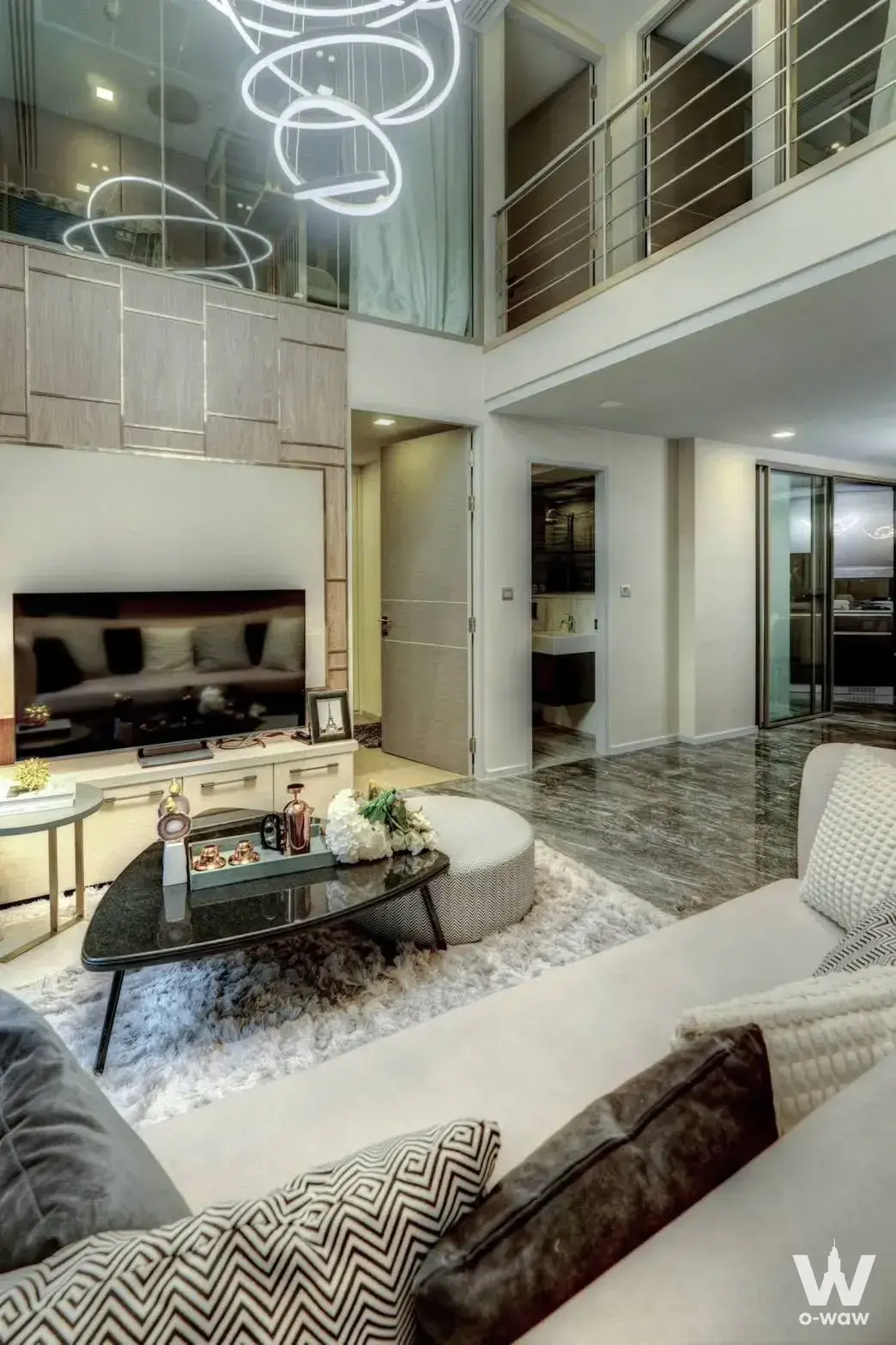 Double-height living room in a 0-bed Culture Chula rental with a sculptural LED chandelier and a marble floor