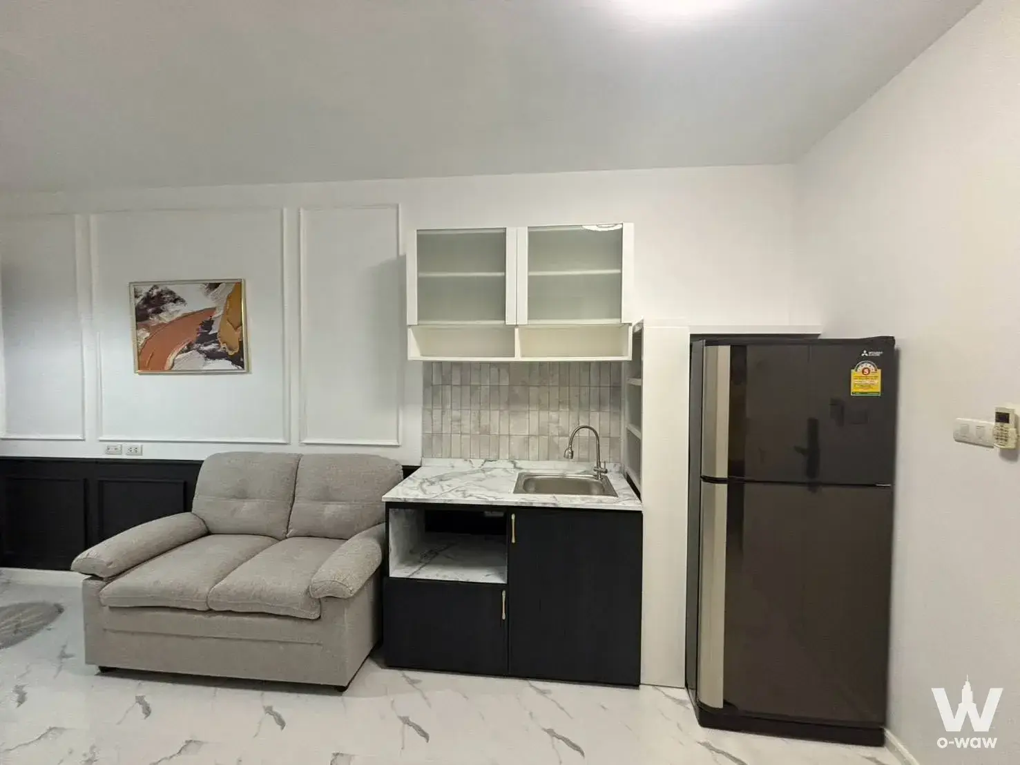 Living room in Condo A Space Kaset with grey sofa, marble tile floor, and compact kitchenette