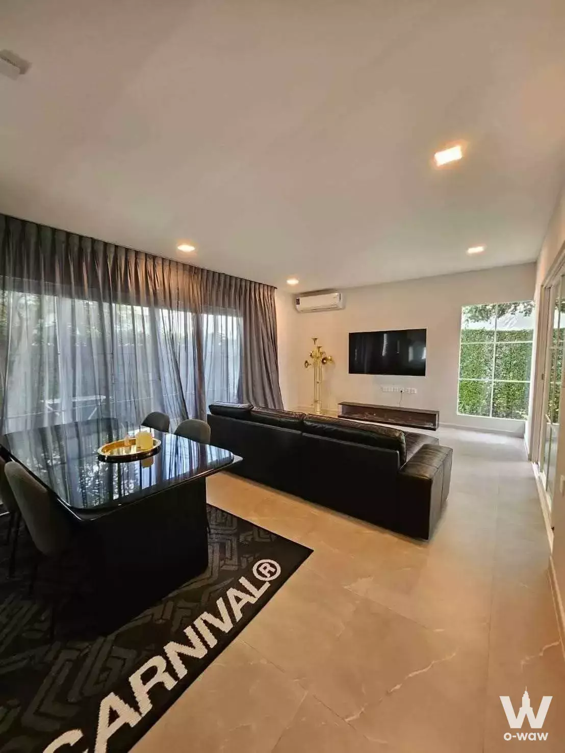 Living room in a Chaiyapruek house featuring a black sectional sofa and gold floor lamp