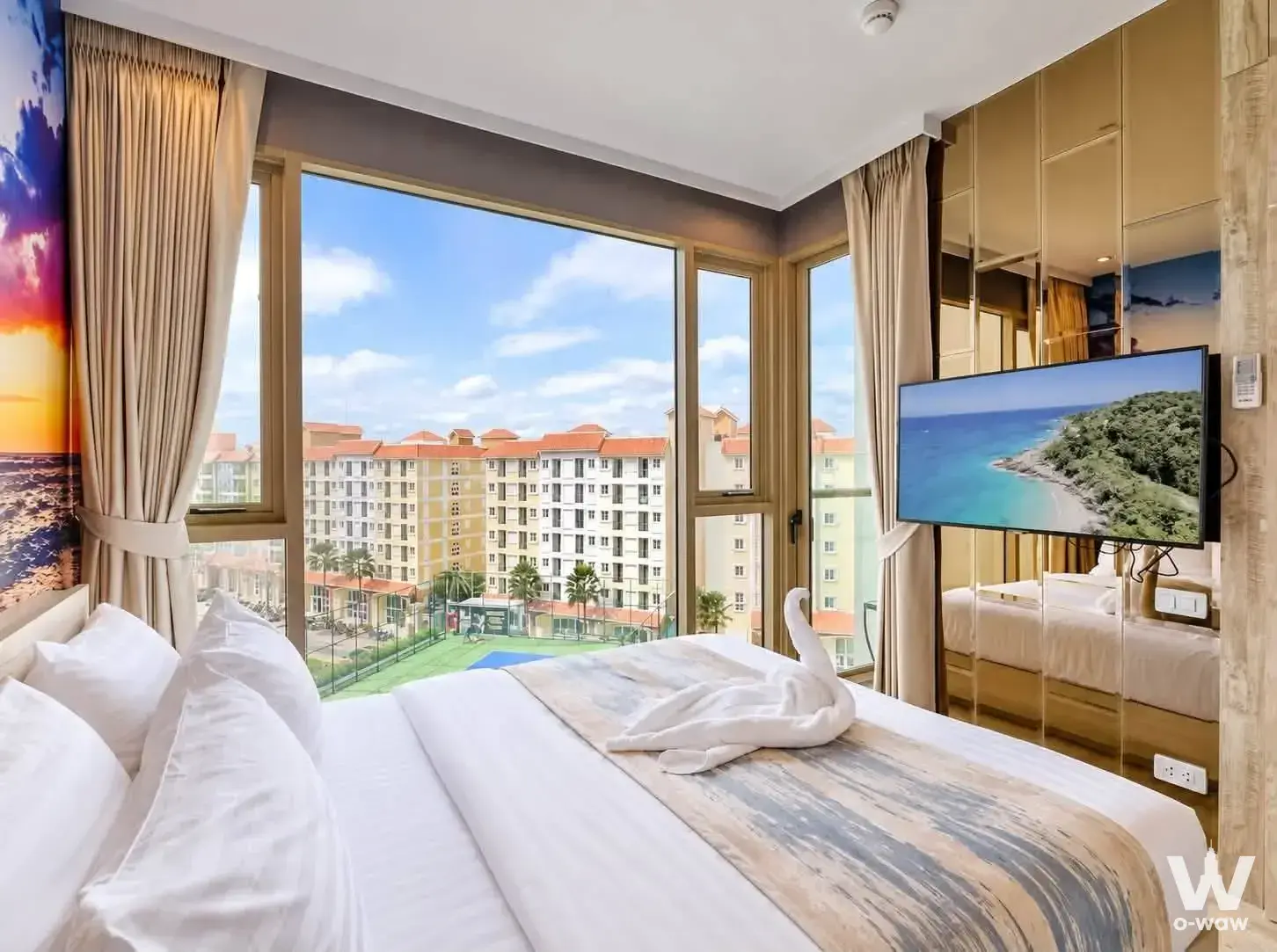 Hotel-style bedroom with sunset ocean mural and city view in The Riviera Monaco 1-bed condo