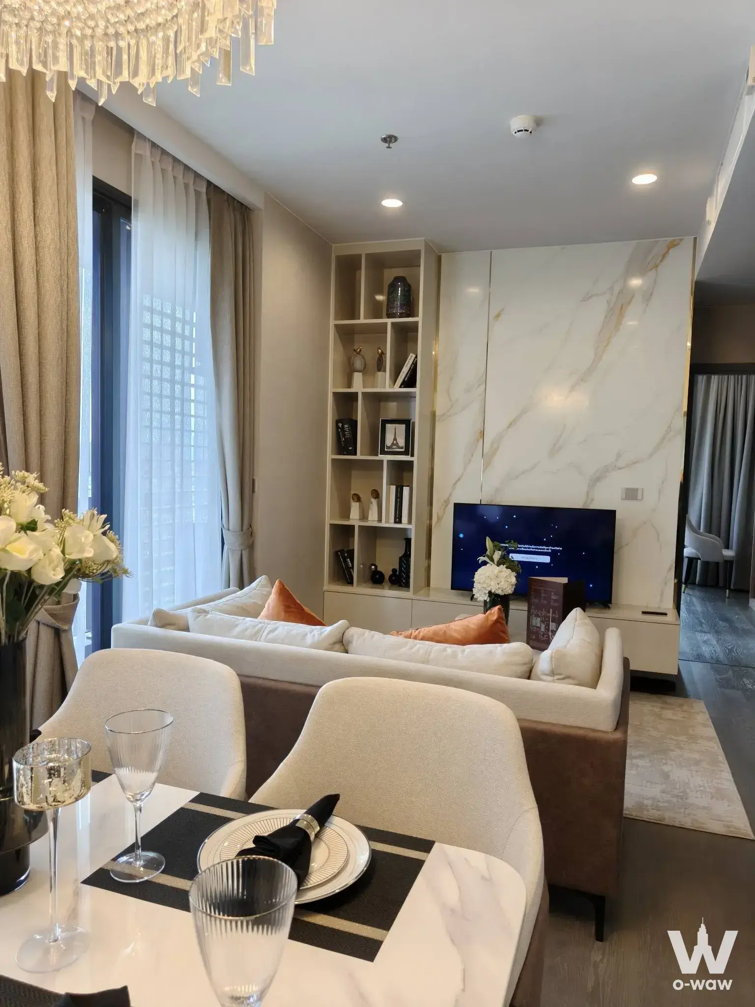 Coco Parc luxury dining room with marble table, crystal chandelier, and beige sofa