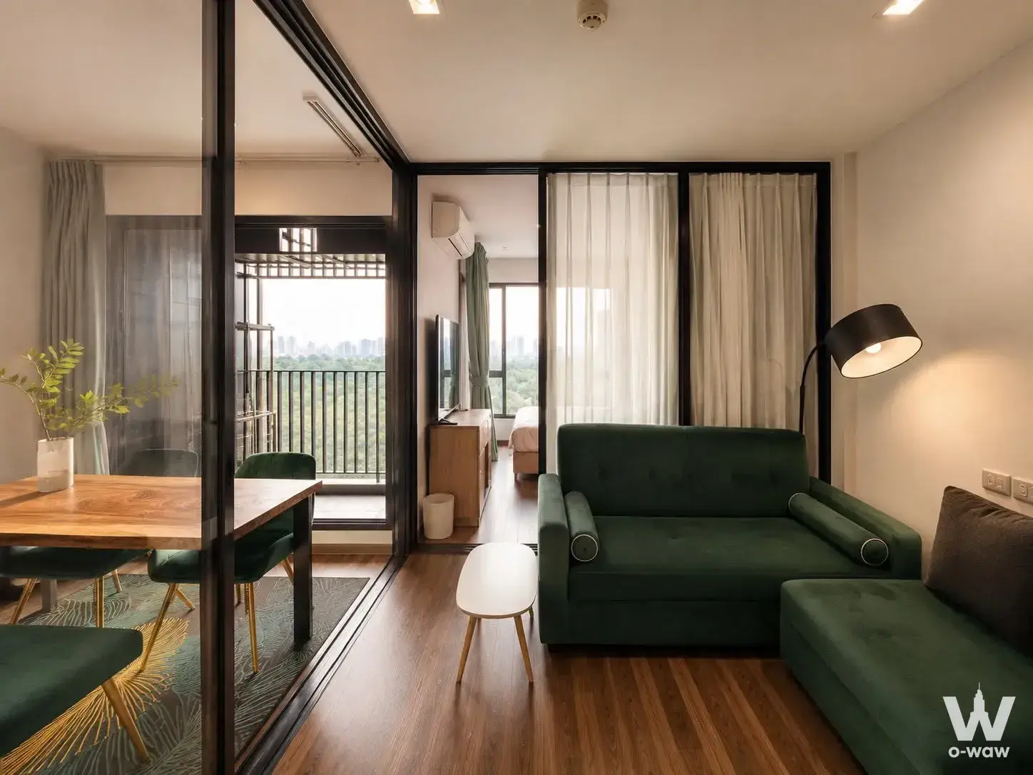 Living room in Life Ladprao Valley with emerald green velvet seating and a city view from the balcony
