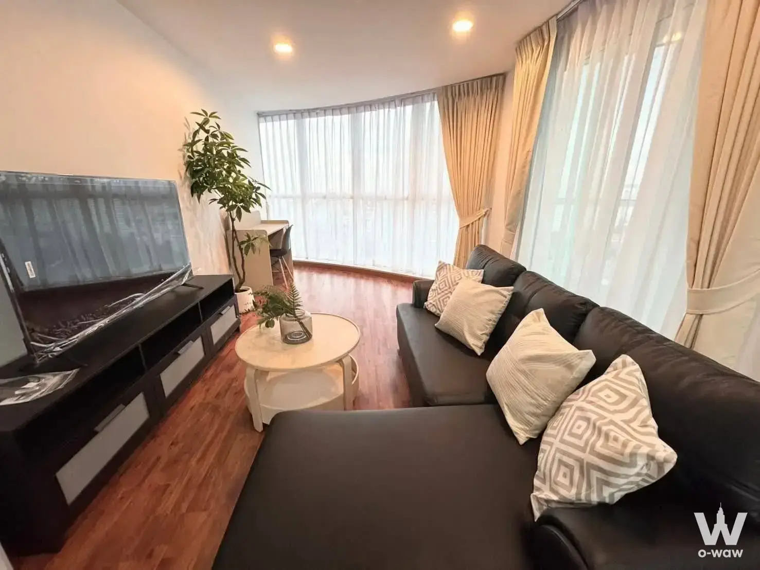 Living room with black sofa and TV in 2-bed Bangkok Horizon Ramkhamhaeng condo