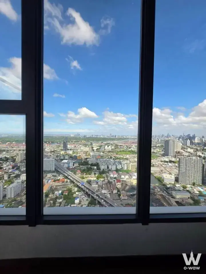 High-floor window view in a 3-bed condo for sale in Siamese Sukhumvit 48 showing blue sky, skyline and elevated highway