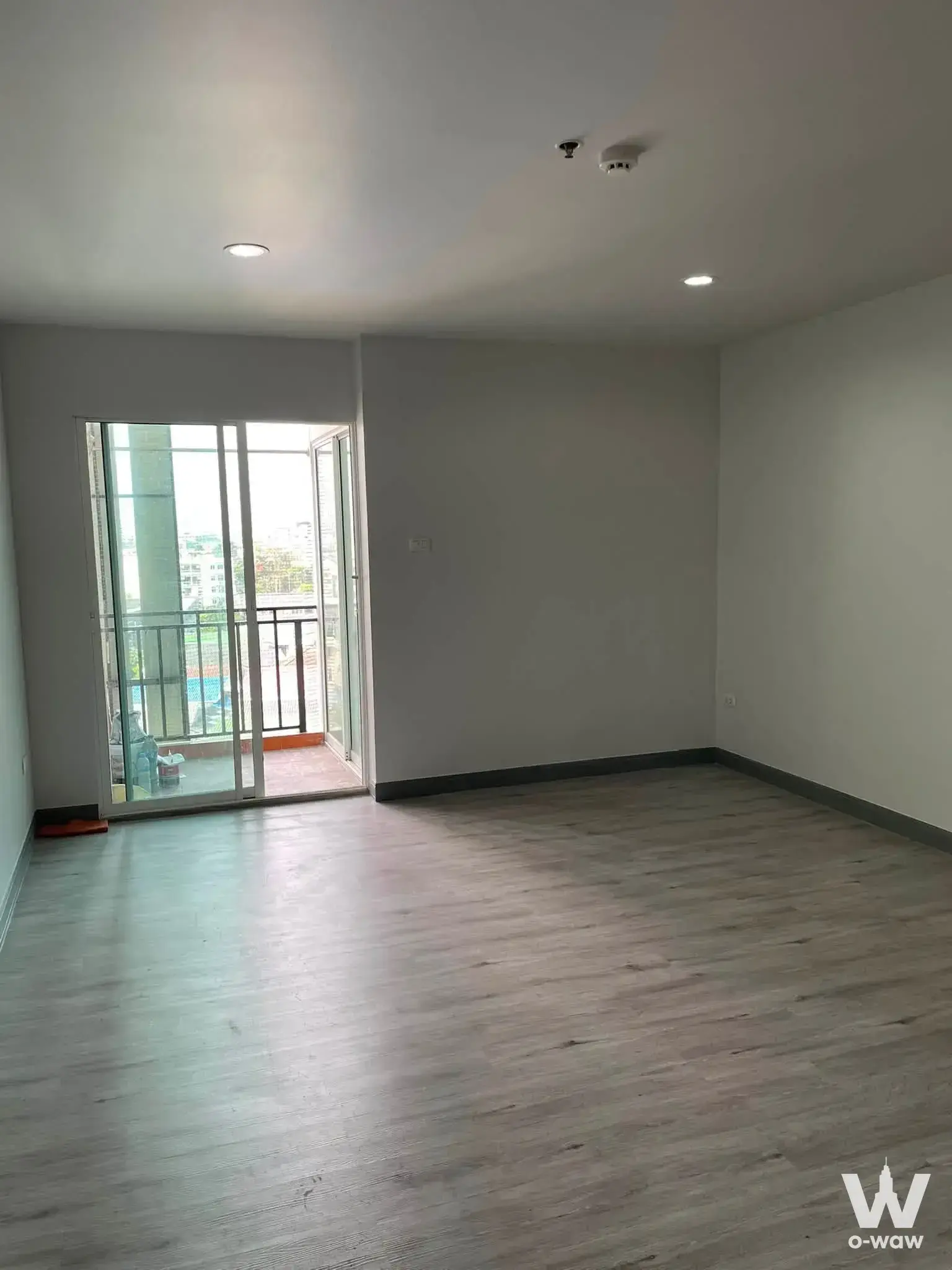Empty unfurnished 1-bed condo for sale in Regent Home 12 with grey laminate flooring and balcony access