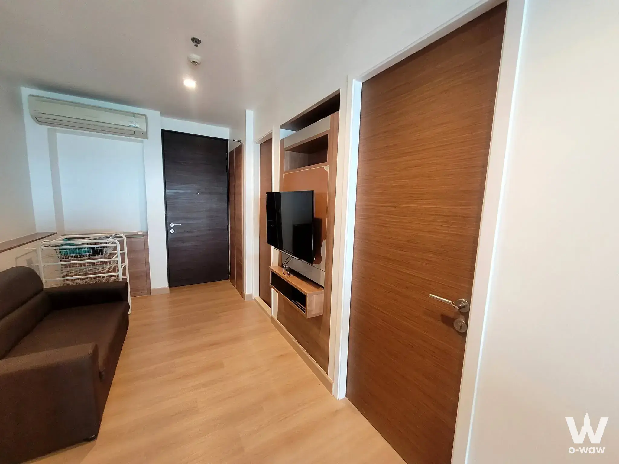 Living room in RHYTHM Phahon-Ari condo with dark sofa and wood media wall