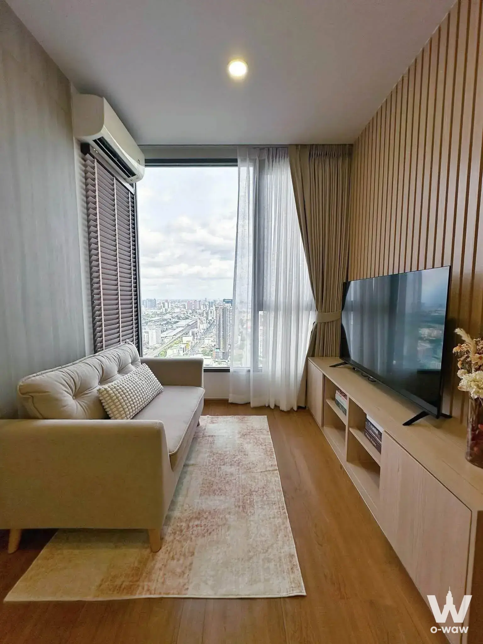 Living room with wood slat accent wall and high-floor city view in Cloud Thonglor-Phetchaburi condo