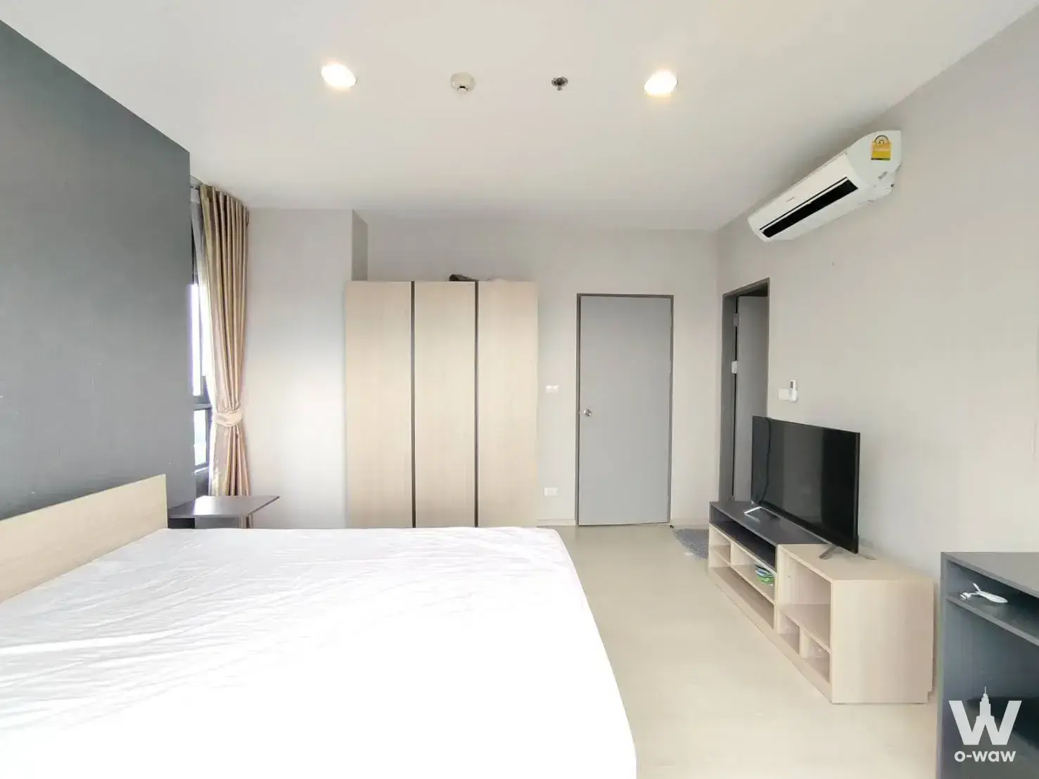 Master bedroom with dark-grey accent wall and light-wood headboard in IDEO Sukhumvit 115
