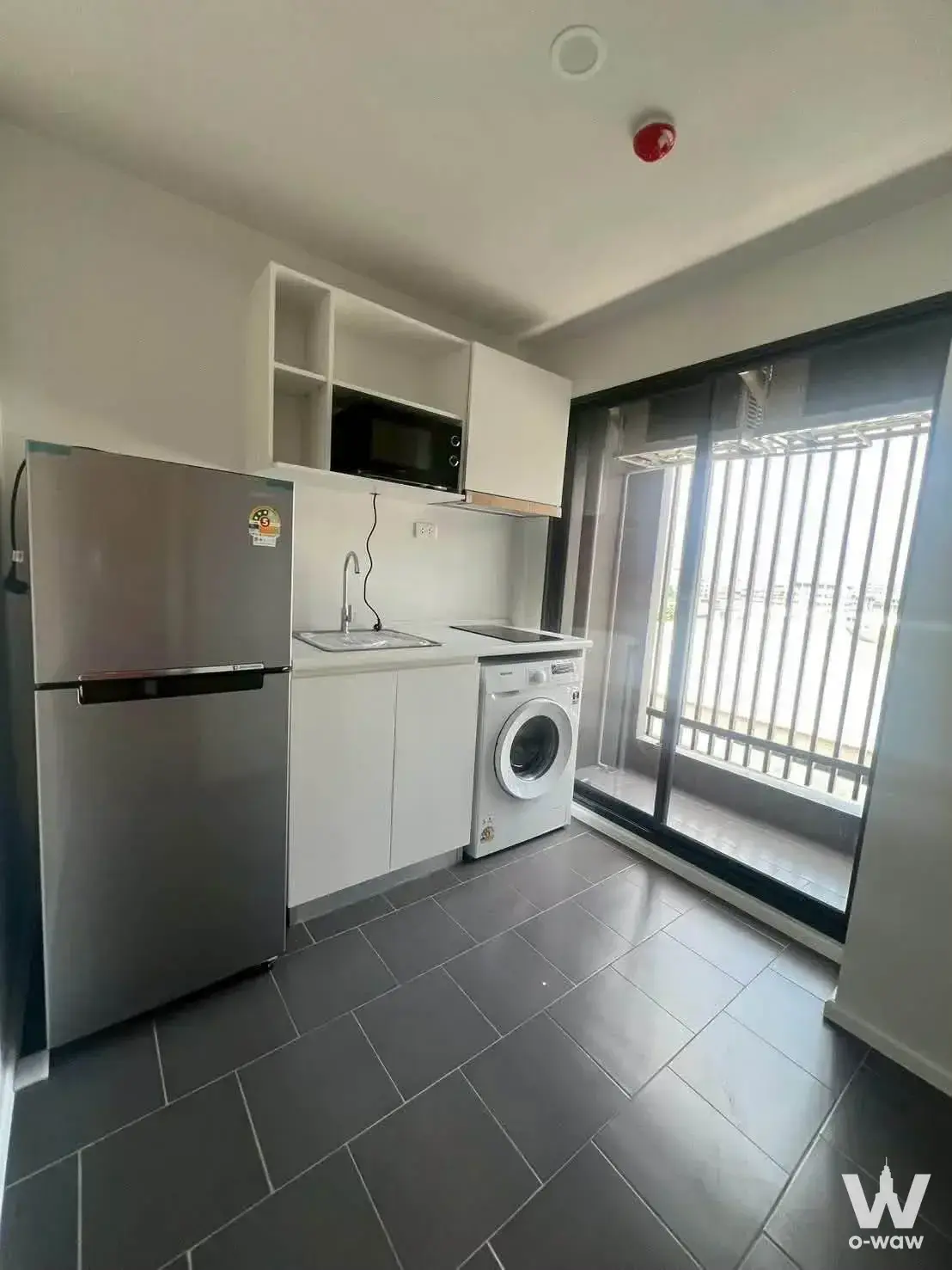 Kitchenette in Blue Sukhumvit 105 condo with stainless steel fridge and black cooktop
