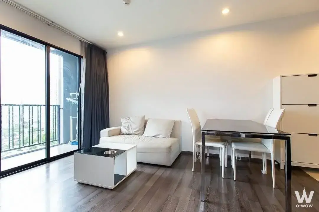 Living room in a 2-bed condo at THE BASE Park West with cream leather sofa and sliding glass doors to balcony