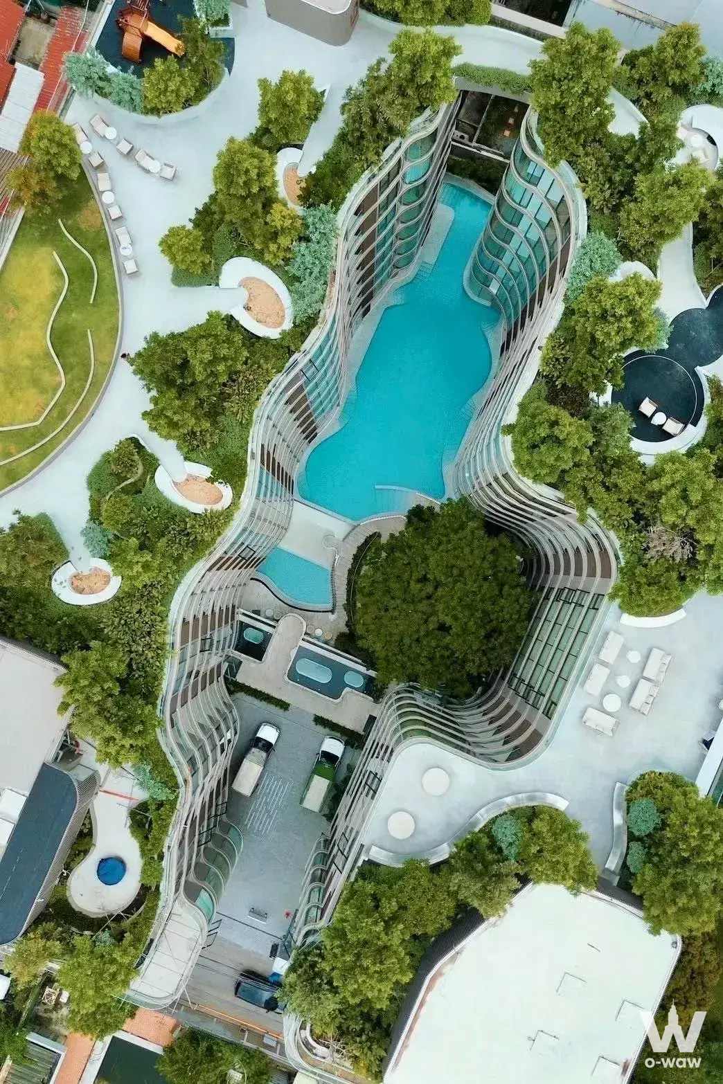 Rooftop infinity pool at Fynn Asoke with curved glass canopy, white loungers, and manicured tropical landscaping