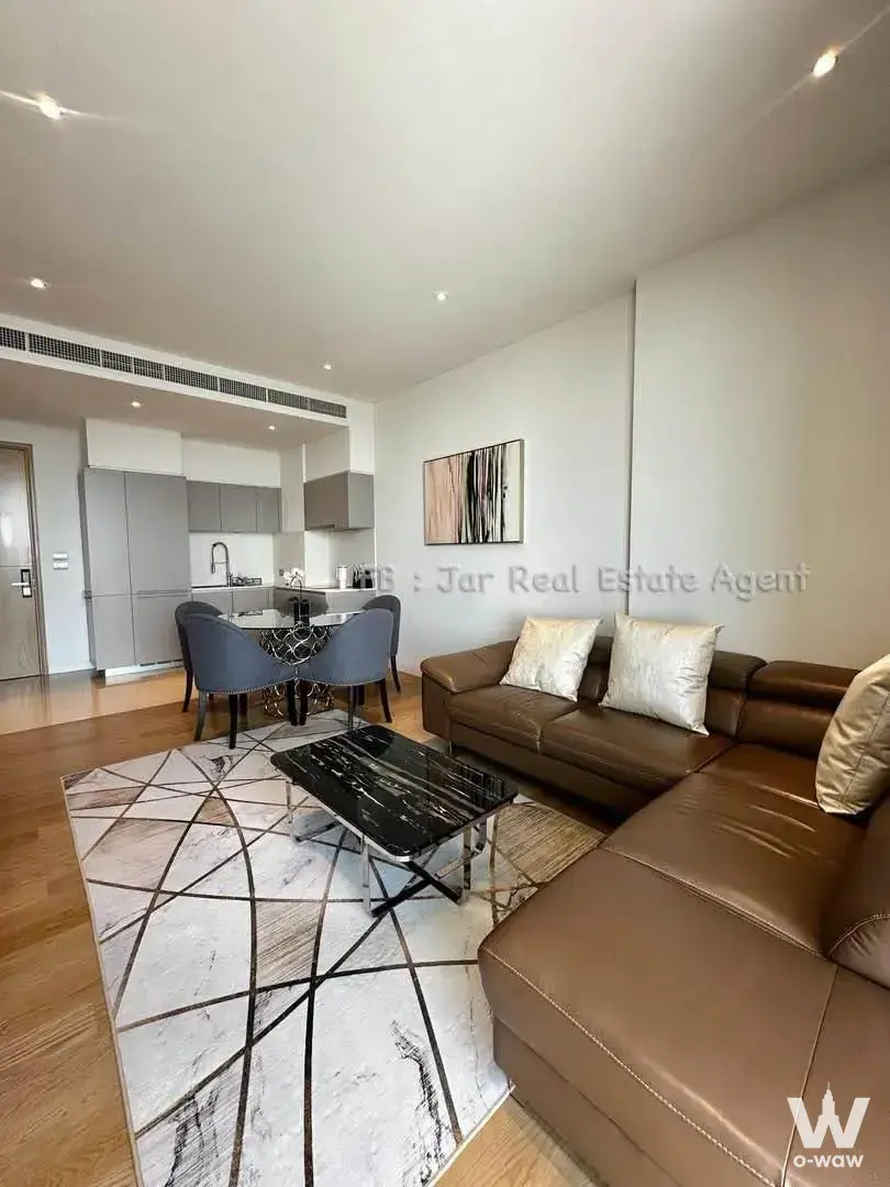 Living room in Magnolias Waterfront Residences with L-shaped leather sectional and round glass dining table