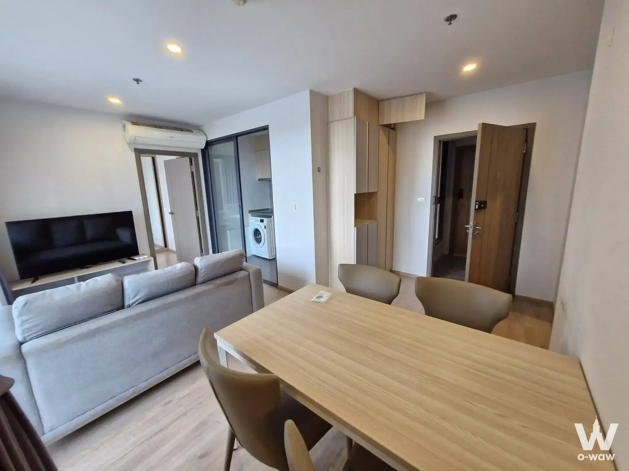 Living room in Ideo O2 with a grey sofa dining table and sliding glass balcony door