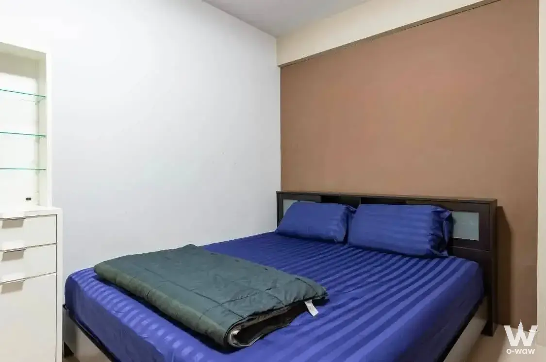Modern 2-bed condo bedroom for sale in Keerasap Mansion Ville with blue striped bedding and tan accent wall