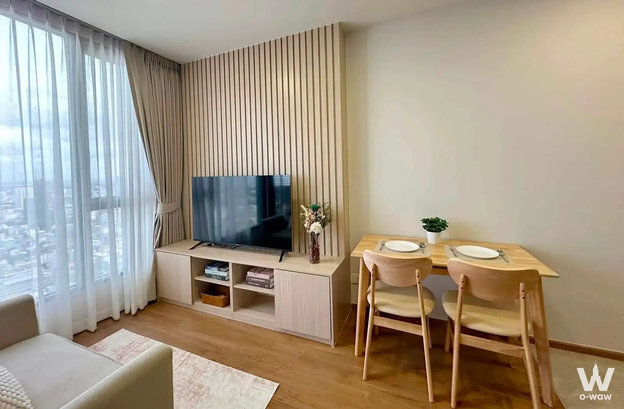 Cloud Thonglor-Phetchaburi 1-bed condo living room with wood accent wall and city skyline view