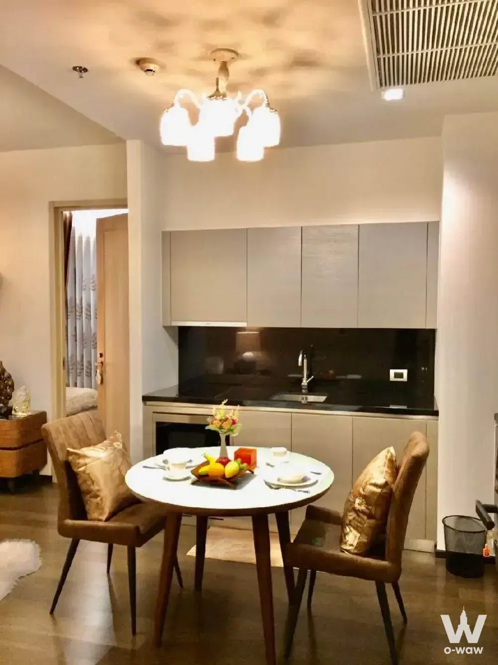 Dining area in a THE XXXIX by Sansiri rental condo with round table, grey cabinets, and warm chandelier lighting