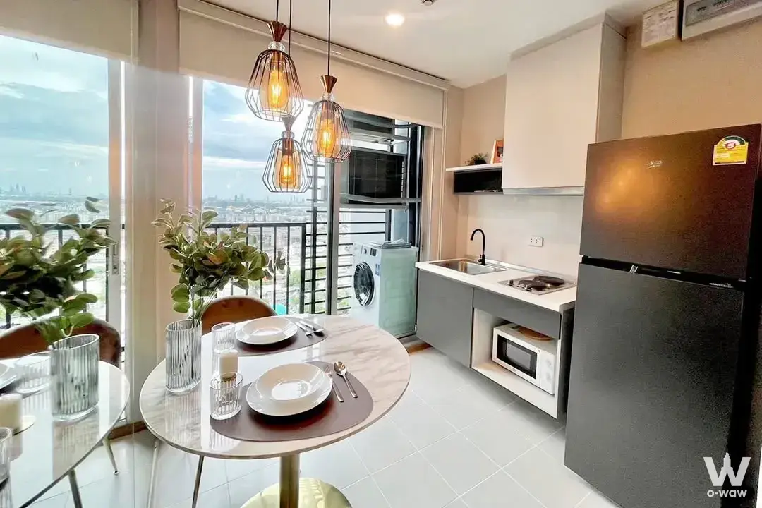 Open-plan kitchen with marble dining table and city views in this 1-bed condo for sale at THE BASE Sukhumvit 77