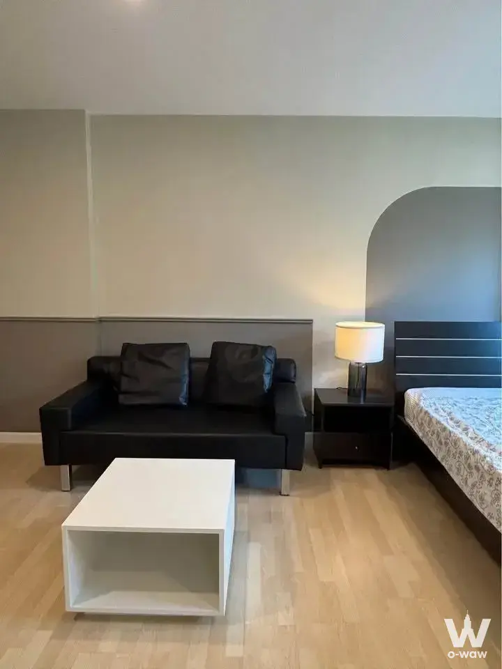 Minimalist studio bedroom for sale in Dcondo Ramindra featuring black faux-leather sofa and wood headboard