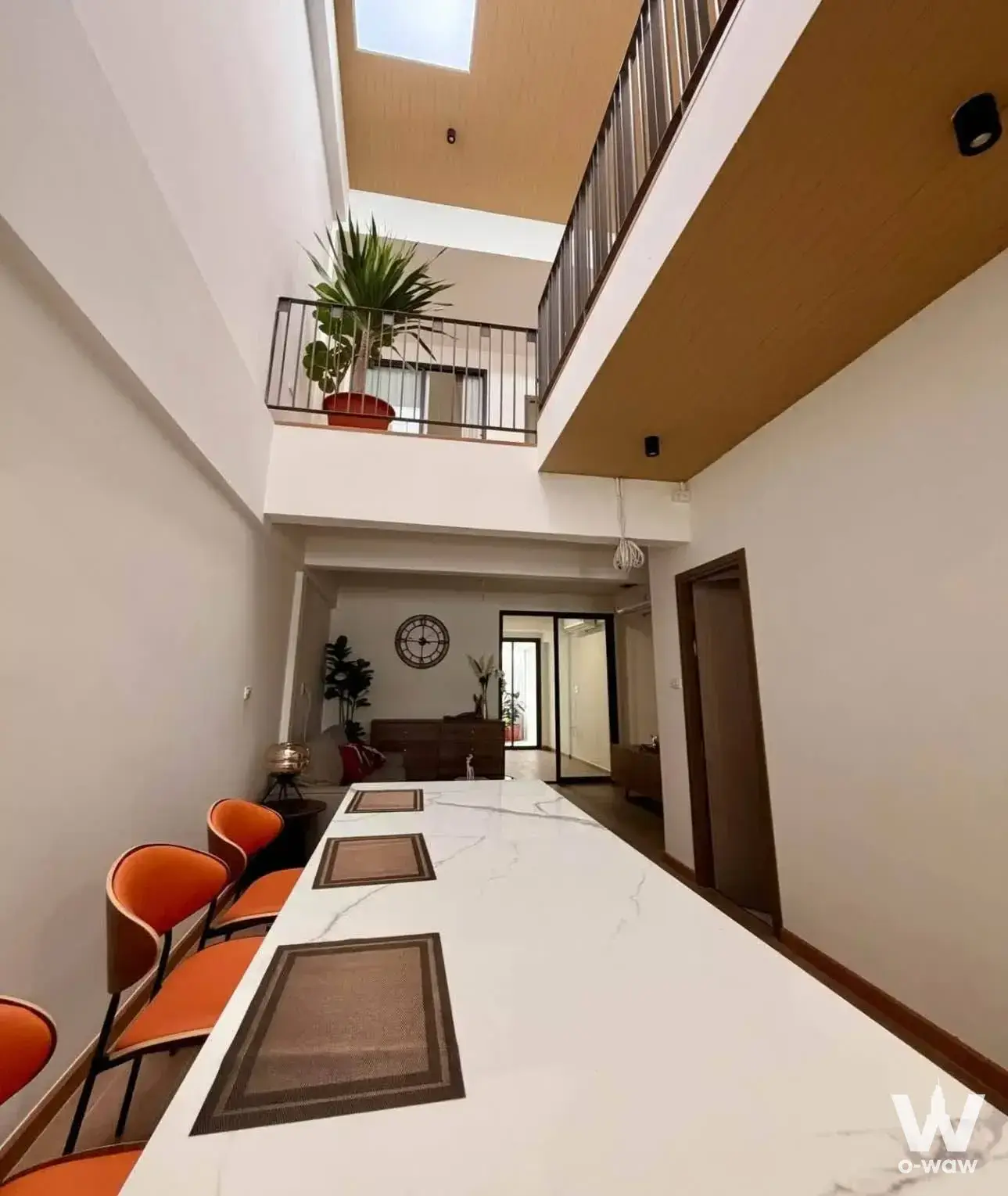 Double-height dining room in a Khlong Tan Niwet 3-bed house featuring a marble table and mezzanine