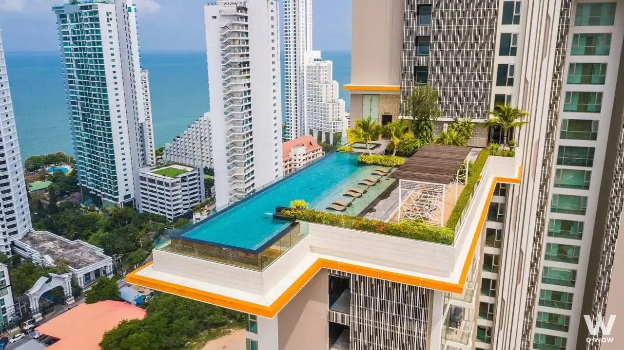 Rooftop infinity pool at The Riviera with wooden loungers, orange accents, and ocean horizon views