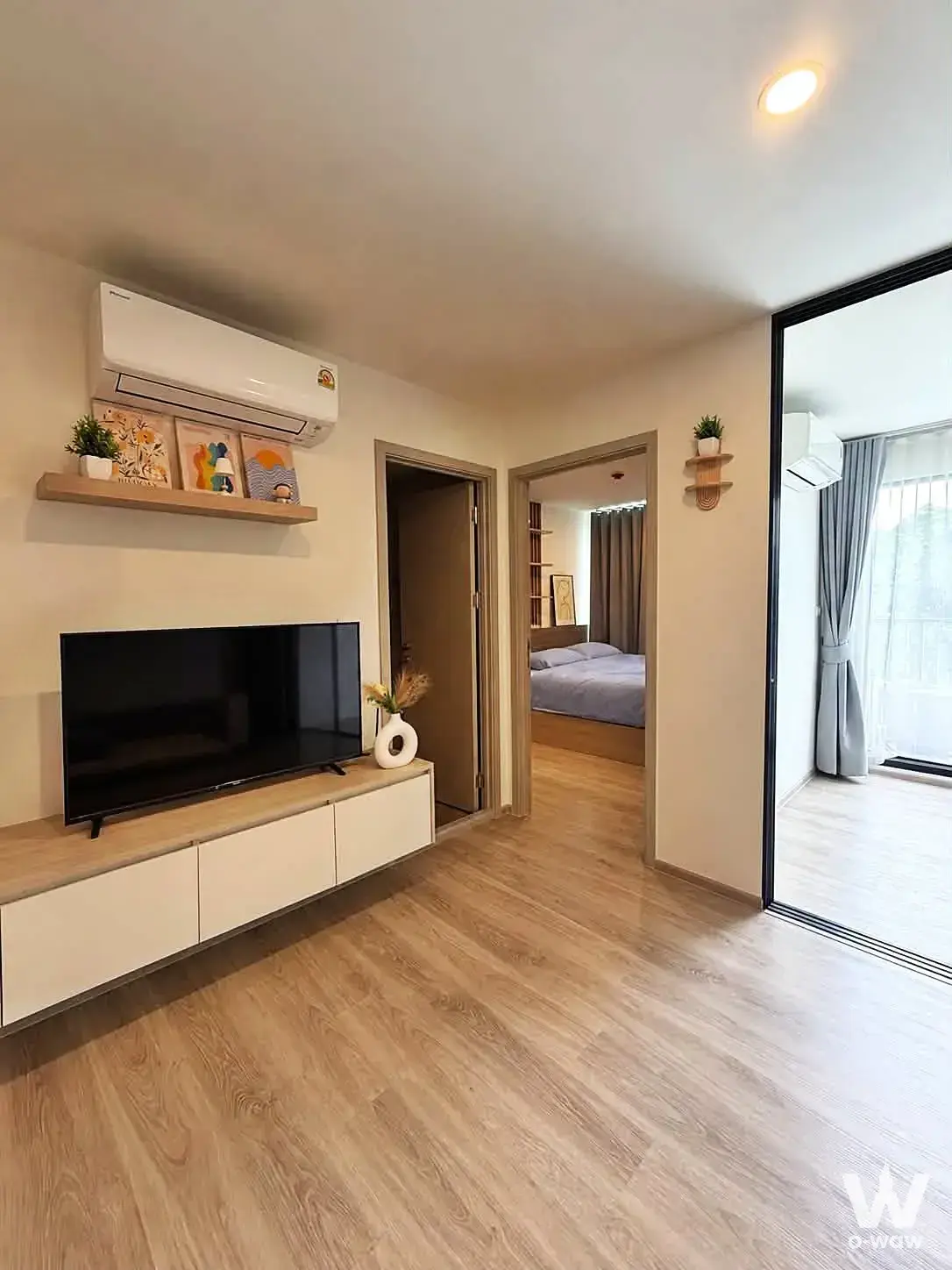 Origin Play Sri Udom Station 1-bed condo living room features wood console and balcony door
